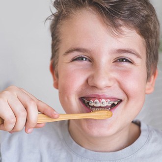 a kid with braces brushing his teeth